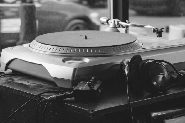 Black and white photo of a turntable with headphones and a phono preamp