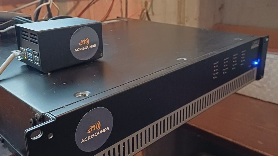 AgriSounds Raspberry Pi 5 and HiFiBerry DAC8x controller mounted next to a 100V-line amplifier in a pig barn's technical room